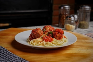 Spaghetti with meatballs and tomato sauce on a white plate, visible in New York.
