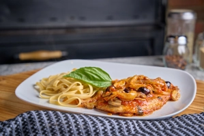 Chicken Scallopini with pasta and basil leaf, featuring mushrooms and olives on a plate in New York.