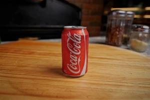 Can of soda on a wooden table with a red and white label, visible in New York.