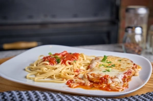 Chicken Parmigiana with melted cheese and tomato sauce, served with pasta in New York.