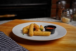 Mozzarella sticks with a crispy coating served with marinara sauce on a white plate in New York.