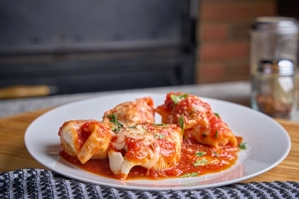 Baked stuffed shells with cheese and tomato sauce, garnished with herbs, from Donabella in New York.