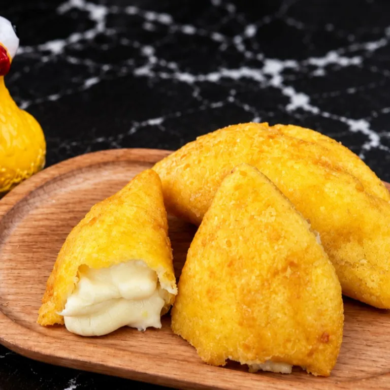 Cheese empanada with melted cheese filling on a wooden plate. The golden crust is visible. Unknown cuisine type in an