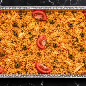 Arroz con pollo en bandeja con rodajas de tomate y aceitunas verdes. Cocina desconocida en ciudad desconocida.