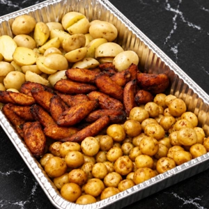 Bandeja de acompañamientos con papas al horno, zanahorias asadas y papas pequeñas en una bandeja de aluminio. Ciudad