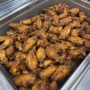 Fried chicken wings with crispy skin in a metal tray, served at a Latin restaurant in Carrollton.