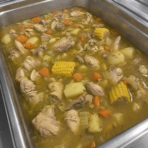Sopa de pollo with chicken pieces, corn, and carrots in Carrollton.