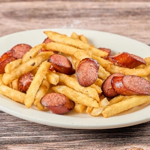 Salchipapas with sliced sausage and fries on a plate at Las Brisas Cafe in Union City.