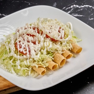 Fried Chicken Taquitos topped with shredded lettuce, sliced tomatoes, and crumbled cheese in Dacula.