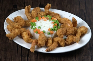 Langostinos with rice topped with peas and carrots, served with fried shrimp. Cuisine type and city unknown.