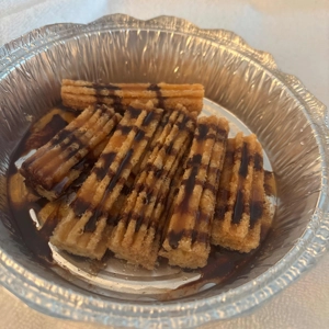 Churros with chocolate drizzle in a foil container, a Spanish dessert in Roanoke.
