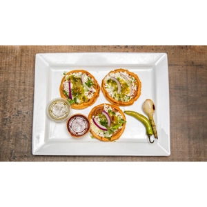 Picaditas with beans, queso fresco, and onions on a white plate. Mexican cuisine in Roanoke.