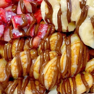 Mini pancakes with strawberries, banana slices, and Nutella drizzle in Jackson Heights.