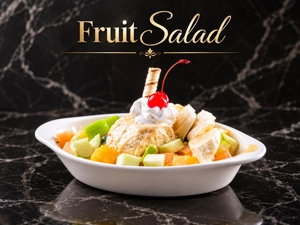 Fruit salad with banana slices, green apple, and a cherry on top, served in a Colombian restaurant in Fairview, NJ.