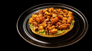 Chunchuarepa with crispy pork and avocado on a tostada. Cuisine type and city unknown.