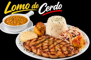 Lomo de cerdo empanizado con arroz blanco y ensalada en plato. Sopa de frijoles en tazón al lado. Ciudad desconocida.