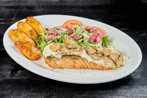 Salmón a la colombiana con champiñones y plátanos maduros, acompañado de ensalada fresca. Ciudad desconocida.