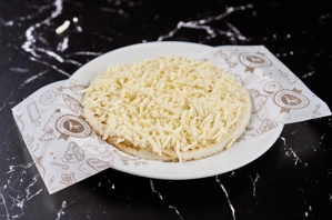 Arepa con queso rallado sobre un plato, típica de la cocina colombiana.