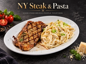 Bistec New York Strip con fettuccine en salsa cremosa, acompañado de tomates frescos y queso parmesano en una mesa.